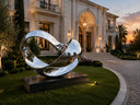 Contemporary stainless steel sculpture displayed in a luxury villa landscape, showing how artwork enhances architectural and outdoor spaces