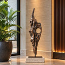 Alongside potted greenery and vertical wood panels, this warm bronze abstract artwork adds a natural mineral texture to a boutique hotel lobby setting. Model BB-034.