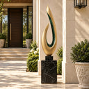 Abstract gold flame sculpture with a green accent displayed in an outdoor courtyard with stone pillars and potted plants, suitable for luxury garden and patio landscape decoration.
