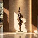 Antique bronze abstract sculpture with a flowing organic shape on a square base, placed against a warm wood-paneled wall, adding contemporary elegance to luxury interior spaces.