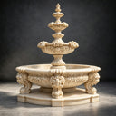 A beige cast stone sculptural fountain, highlighting the ornate detailing of its lower basin, photographed against a dark studio backdrop for catalog display.