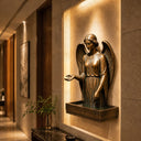 Bronze angel sculpture displayed in a luxury interior space with architectural lighting and elegant religious art design