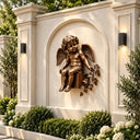 Bronze cherub angel wall sculpture with wings mounted on a beige arched wall in an outdoor courtyard, paired with wall lamps and greenery as high-end garden wall decor, highlighting classic European artistic style.