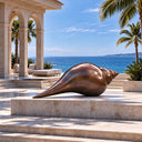 A detailed bronze seashell sculpture with an elongated conch design, complementing a poolside terrace and luxury nautical decor.