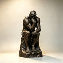 Side view of a bronze Thinker sculpture on a light background, showing its refined casting details and contemplative posture for high-end art reference.