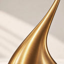 Close-up of the flowing curved body and brushed gold finish on a stainless steel sculptural fountain
