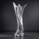 Photographed against a dark studio backdrop, this brushed metal landscape sculpture highlights the sleek curves of its abstract forms for design catalogs.