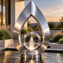 Brushed stainless steel geometric ring fountain creating a water feature for a contemporary landscaped garden
