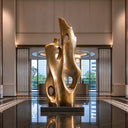 A cast bronze sculpture with organic curved surfaces and open forms, standing in a modern indoor corridor with glass walls and wooden framing. Model BB-033.