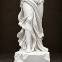 Close-up of a white marble statue draped robe details on a dark background, showcasing the fine carving texture and classical craftsmanship of the sculpture.