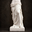 Close-up of a white marble statue draped robe and leg details on a dark background, showcasing fine carving texture and classical sculpture craftsmanship.