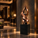 Anchored by a geometric black base, this contemporary bronze ribbon sculpture exhibits intertwined metallic curves, configured for a luxury hotel entrance.
