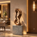 Taking the form of a twisted infinity loop, this contemporary bronze sculpture is positioned within a modern executive office as custom bronze artwork.