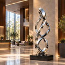 Fabricated from reflective stainless steel, this contemporary entrance sculpture presents a twisted geometric silhouette, representing an abstract metal ribbon sculpture.