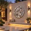 Mounted on an exterior stone wall, this contemporary outdoor wall sculpture displays a swirling reflective surface, enhancing a modern courtyard setting.