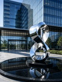 Custom stainless steel sculpture installation at a modern corporate entrance with architectural surroundings