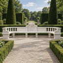 This curved marble garden bench presents a carved central crest and classical balusters, defining the axis of a formal garden landscape with refined stone seating.

