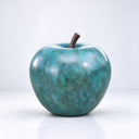 Captured in a studio setting, this custom bronze apple artwork highlights the textured verdigris patina and smooth curves of the monumental fruit sculpture.