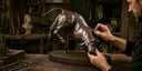 Craftsman hand-finishing a custom bronze bull sculpture in a workshop