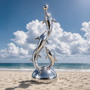 Sculpted to resemble a leaping marine group, this custom dolphin sculpture accentuates the coastal beauty of a sandy beach setting.