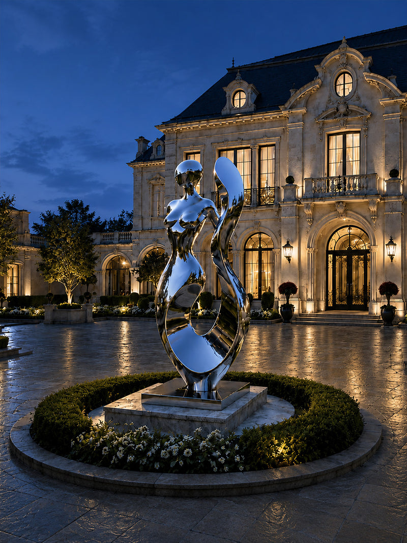 Night view of fluid human design of a contemporary stainless steel sculpture