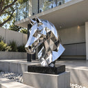 Contemporary geometric horse head sculpture in reflective stainless steel displayed outside a modern building