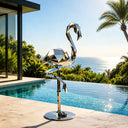 Geometric stainless steel sculpture installed in a luxury villa garden with modern landscape design and contemporary architectural surroundings
