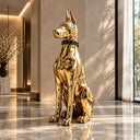 Gold stainless steel dog sculpture with a mirror-polished finish displayed in a luxury hotel lobby with marble flooring, elegant stone walls, and natural daylight.