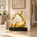 Golden antelope statue displayed in a modern hallway with framed art and plants, adding a luxurious and elegant touch to interior space and console table decoration.

