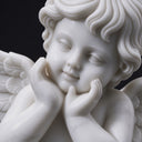 Close-up view of a hand-carved marble cherub face, showing the fingers resting under the chin against a dark backdrop.