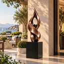 Rising from a solid black plinth, this large abstract bronze flame sculpture boasts a twisting, ribbon-like form, devised for a seaside resort terrace.