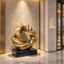 Exhibiting a flowing, golden form, this large abstract bronze ribbon sculpture is poised on a black marble base for a luxury hotel lobby.