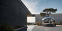 Large stainless steel sculpture with a highly reflective finish in a modern architectural courtyard