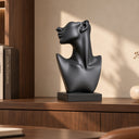Portraying a confident upward gaze, this matte black abstract female bust sculpture symbolizes inner strength, suited for display within luxury homes.