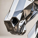 Close-up of the sculpted eye and angular muzzle of a mirror-polished geometric stainless steel horse head