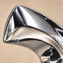 Close-up of the sweeping curved metal surface and reflective mirror-polished finish of a contemporary abstract stainless steel sculpture.
