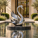 A mirror polished stainless steel swan sculpture placed on an outdoor water pool, reflecting the modern building facade and surrounding greenery. Model SS-001.