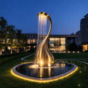 Gold stainless steel sculptural fountain with cascading water in a luxury villa garden at night