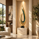 Modern abstract gold teardrop sculpture with a green inlay accent on a black base, placed in a luxury living room with beige sofas and marble surfaces, ideal for high-end interior art decoration.