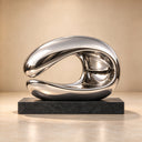 Studio imagery of a polished stainless steel wave sculpture against a neutral backdrop, detailing its seamless finish and organic contours for design catalogs.