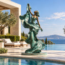 Framed by curling green drapery, this bronze female dancer pairs warm bronze accents with a circular base on a villa poolside terrace.
