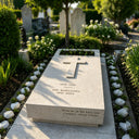 Enveloped by white blooms and verdant foliage, this beige granite ledger stone with a carved cross and personalized inscription rests harmoniously within a tranquil memorial park.