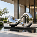 Mirror-polished stainless steel wave sculpture SS-029 in a contemporary architectural courtyard surrounded by glass and stone
