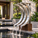Stainless steel outdoor water feature SS-031 with three curved channels installed beside a contemporary courtyard pool