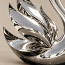Close-up detail of a stainless steel swan sculpture, showing the sharp metallic finish and layered feather textures of the wing structure. Model SS-001.