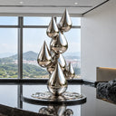 Contemporary mirror-polished stainless steel water drop sculpture above a reflective pool in a minimalist luxury interior