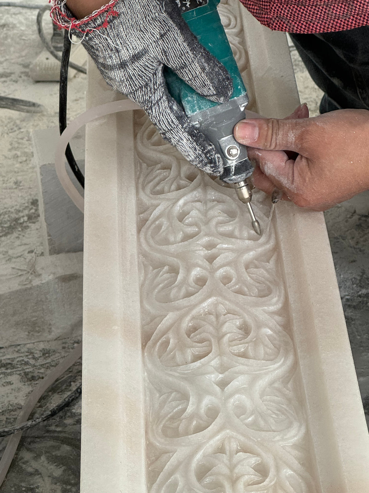 Craftsman carving intricate floral details into a natural stone sculpture panel