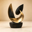 The abstract bronze leaf sculpture shows mottled dark surfaces, gold edges and a broad crescent-like curve above a rounded base in a studio setting.