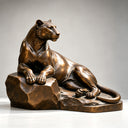 Studio shot of a bronze lioness sculpture reclining on a rock on a light background, highlighting detailed casting texture and elegant posture for art decor product display and reference.