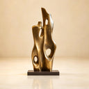 Studio shot of a modern abstract gold sculpture featuring a tall vertical organic form with cutouts on a black base against a beige background, highlighting its polished metallic finish for art decor product display and reference.

